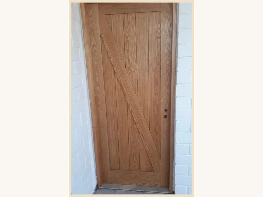 Puerta de abatir MDF modelo caballeriza con canterías verticales enchapada en Encina Roja
